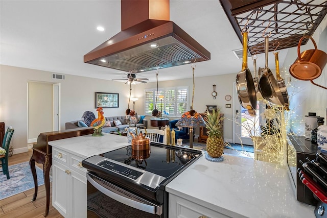 621 77th Ave, St Pete Beach, FL 33706 - kitchen featuring island range hood, stainless steel range with electric cooktop, white cabinetry, light wood finished floors, and open floor plan
