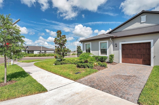31530 Magna Gulf Loop, San Antonio, FL 33576 - view of home's exterior featuring stucco siding, a garage, a lawn, and decorative driveway