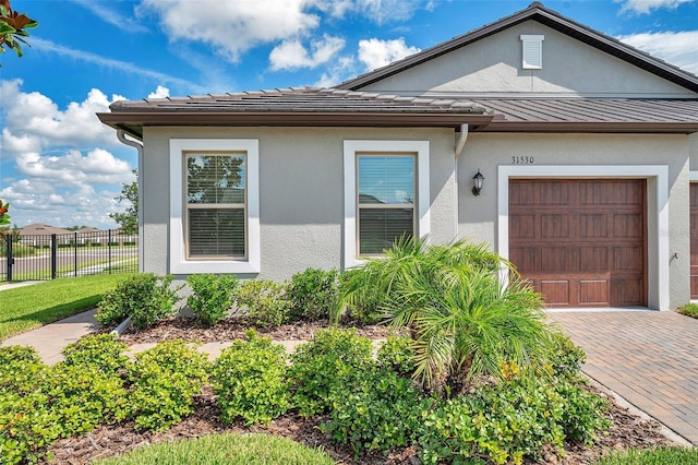 31530 Magna Gulf Loop, San Antonio, FL 33576 - view of front of home featuring a standing seam roof, stucco siding, a metal roof, an attached garage, and decorative driveway