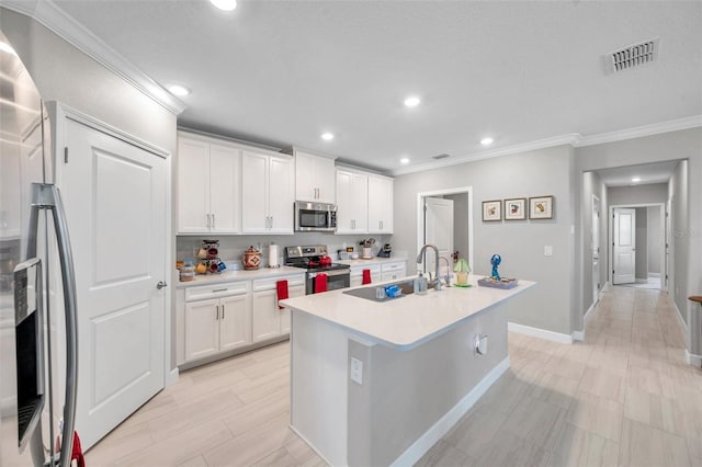 31530 Magna Gulf Loop, San Antonio, FL 33576 - kitchen with stainless steel appliances, crown molding, a center island with sink, white cabinetry, and light countertops