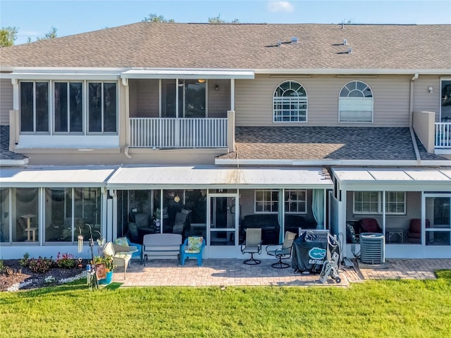 8251 118th Ave Unit 8251, Largo, FL 33773 - rear view of property featuring a balcony, a sunroom, a shingled roof, a patio area, and a yard