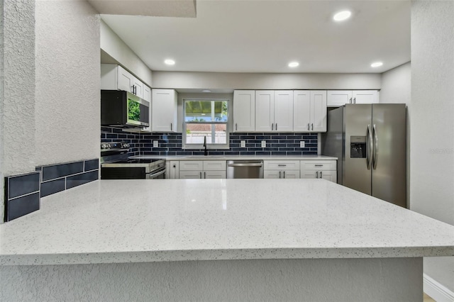 7806 N Matanzas Ave, Tampa, FL 33614 - kitchen with stainless steel appliances, decorative backsplash, white cabinets, light stone counters, and recessed lighting