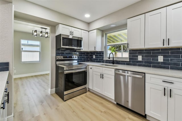 7806 N Matanzas Ave, Tampa, FL 33614 - kitchen with appliances with stainless steel finishes, light wood-style flooring, tasteful backsplash, white cabinets, and light countertops