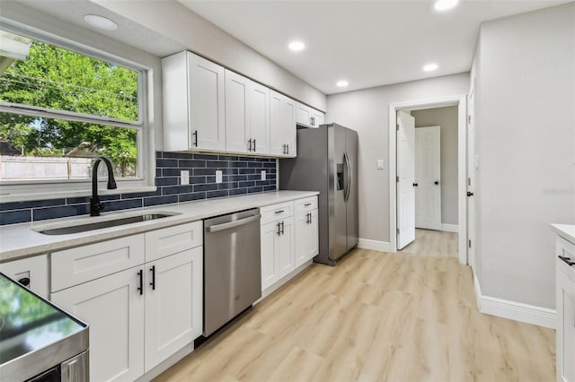 7806 N Matanzas Ave, Tampa, FL 33614 - kitchen with stainless steel appliances, light countertops, backsplash, light wood finished floors, and white cabinetry