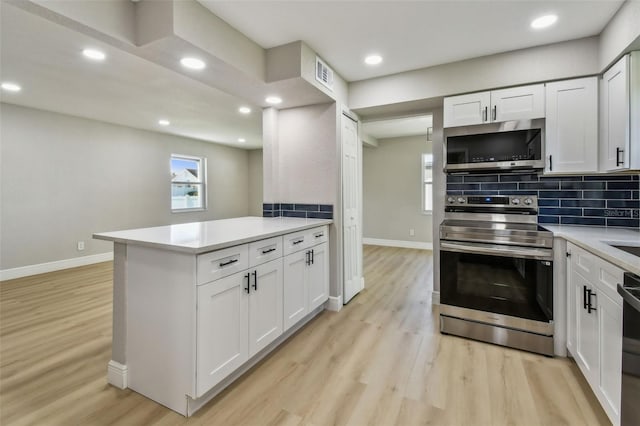 7806 N Matanzas Ave, Tampa, FL 33614 - kitchen featuring appliances with stainless steel finishes, light wood finished floors, tasteful backsplash, white cabinets, and recessed lighting