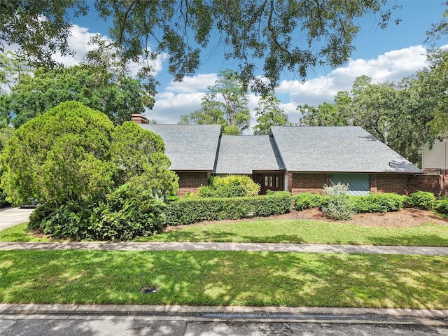 4128 Carrollwood Village Dr, Tampa, FL 33618 - view of front of property with a front lawn, brick siding, a chimney, and roof with shingles