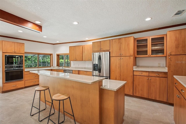 4128 Carrollwood Village Dr, Tampa, FL 33618 - kitchen with black appliances, a breakfast bar, brown cabinets, glass insert cabinets, and a textured ceiling