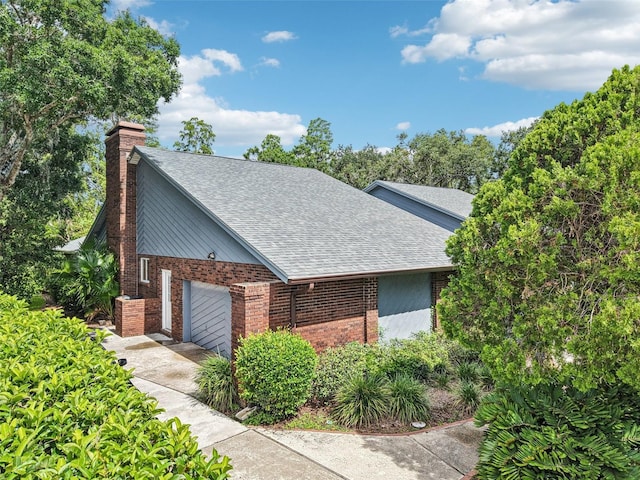 4128 Carrollwood Village Dr, Tampa, FL 33618 - view of side of property with a shingled roof, brick siding, a chimney, an attached garage, and concrete driveway