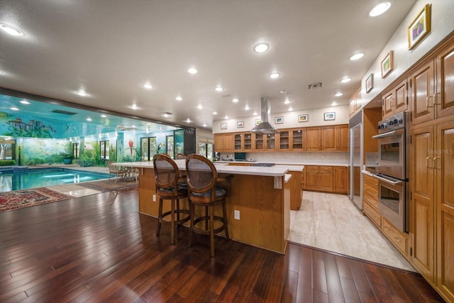 1835 Alicia Way, Clearwater, FL 33764 - kitchen with double oven, brown cabinets, light countertops, a kitchen bar, and recessed lighting