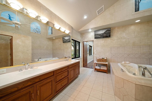 1835 Alicia Way, Clearwater, FL 33764 - bathroom with tile walls, vaulted ceiling, tile patterned flooring, a bath, and double vanity
