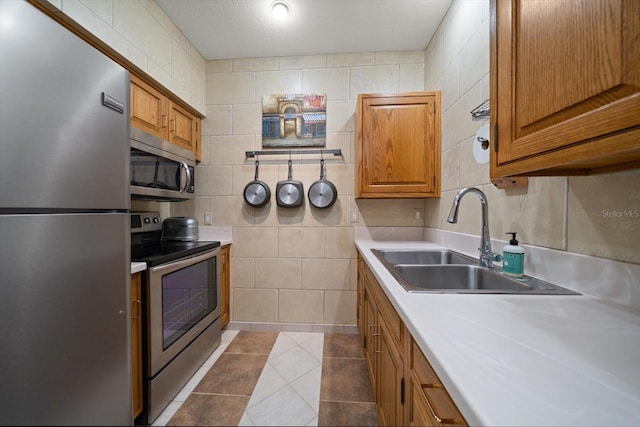 1835 Alicia Way, Clearwater, FL 33764 - kitchen with appliances with stainless steel finishes, brown cabinetry, light countertops, tile walls, and dark tile patterned floors