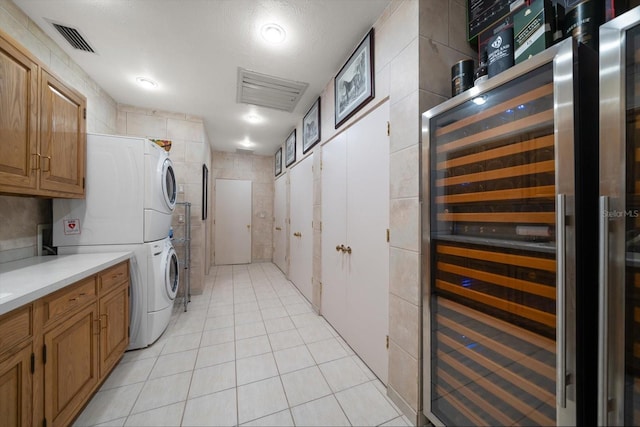 1835 Alicia Way, Clearwater, FL 33764 - washroom with wine cooler, estacked washer and dryer, tile walls, cabinet space, and light tile patterned flooring