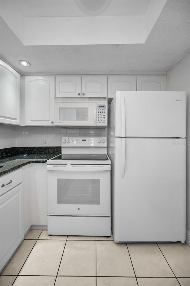 920 Virginia St Unit 204, Dunedin, FL 34698 - kitchen with white appliances, white cabinetry, light tile patterned floors, and dark stone countertops