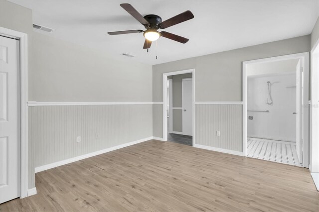 271 Eastpoint Ct, Spring Hill, FL 34606 - unfurnished bedroom featuring wood finished floors, wainscoting, connected bathroom, and a ceiling fan