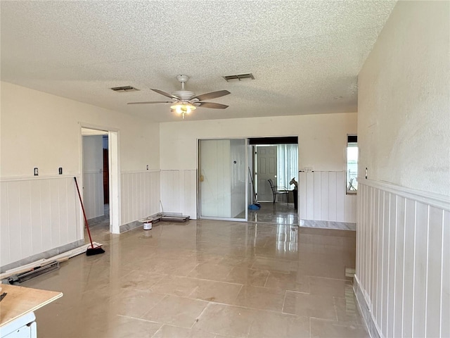 6711 Arroyo Dr, New Port Richey, FL 34652 - spare room featuring ceiling fan, a textured ceiling, and a wainscoted wall