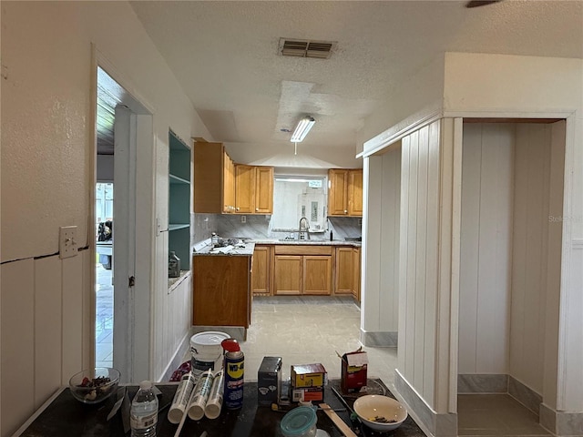 6711 Arroyo Dr, New Port Richey, FL 34652 - kitchen with light countertops, brown cabinetry, a textured ceiling, and tasteful backsplash