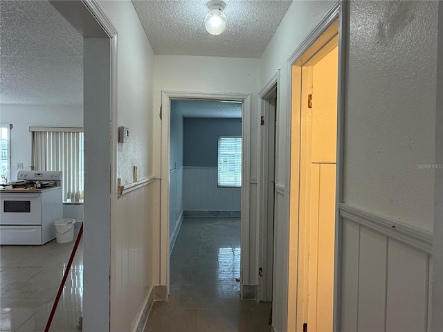 6711 Arroyo Dr, New Port Richey, FL 34652 - corridor featuring a textured ceiling, a wainscoted wall, a decorative wall, and tile patterned floors