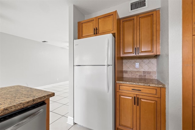 1724 Adams Cir S, Largo, FL 33771 - kitchen with freestanding refrigerator, stainless steel dishwasher, backsplash, light tile patterned floors, and brown cabinetry