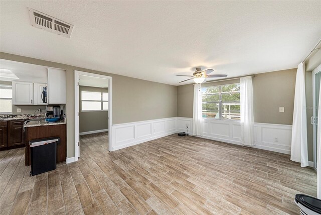 15525 Old Dixie Hwy, Hudson, FL 34667 - unfurnished living room with a ceiling fan, light wood finished floors, plenty of natural light, a decorative wall, and a textured ceiling