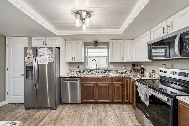 15525 Old Dixie Hwy, Hudson, FL 34667 - kitchen featuring stainless steel appliances, a raised ceiling, light wood-style flooring, white cabinets, and crown molding