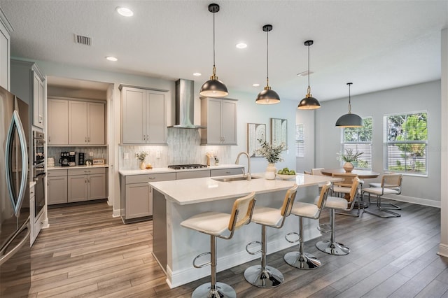 14626 Horse Trot Rd, Lithia, FL 33547 - kitchen featuring wall chimney range hood, gray cabinets, light wood finished floors, backsplash, and light countertops