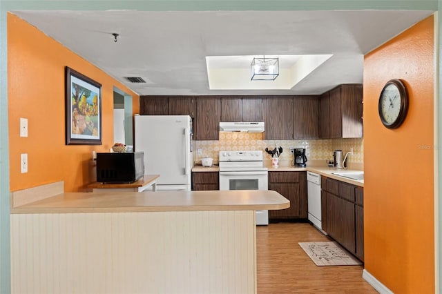 9171 Horizon Dr, Spring Hill, FL 34608 - kitchen with under cabinet range hood, white appliances, a peninsula, light countertops, and light wood-style floors