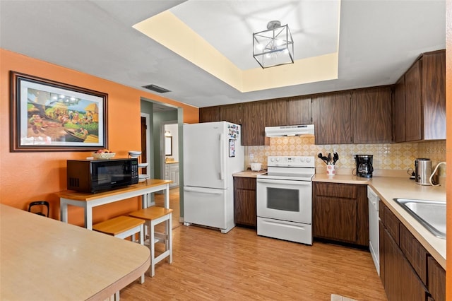 9171 Horizon Dr, Spring Hill, FL 34608 - kitchen with white appliances, under cabinet range hood, light countertops, and decorative backsplash