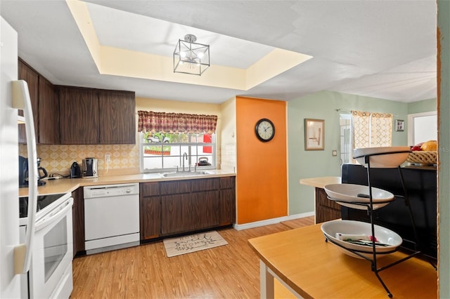 9171 Horizon Dr, Spring Hill, FL 34608 - kitchen with white appliances, light countertops, light wood finished floors, a raised ceiling, and decorative backsplash