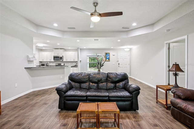 14509 Mayer Ave, Hudson, FL 34669 - living room featuring wood finished floors, a ceiling fan, recessed lighting, and a tray ceiling