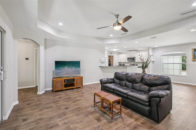 14509 Mayer Ave, Hudson, FL 34669 - living area featuring a ceiling fan, arched walkways, wood finished floors, recessed lighting, and a tray ceiling