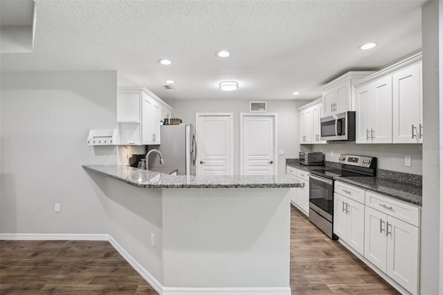 14509 Mayer Ave, Hudson, FL 34669 - kitchen featuring stainless steel appliances, a peninsula, white cabinetry, dark wood finished floors, and recessed lighting