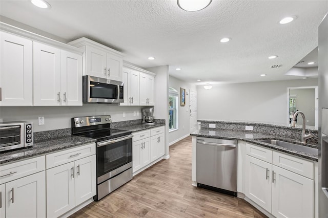 14509 Mayer Ave, Hudson, FL 34669 - kitchen with appliances with stainless steel finishes, a textured ceiling, white cabinets, recessed lighting, and light wood-style flooring
