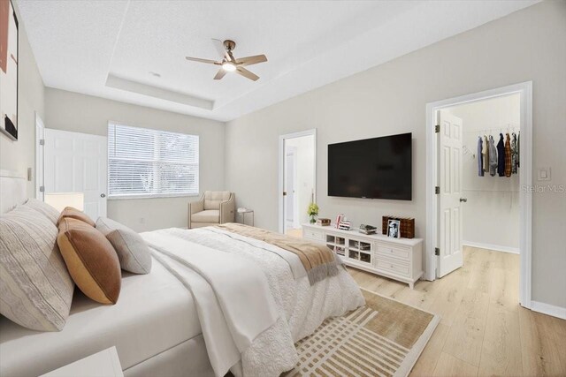 1760 Mountclair Ct, Mount Dora, FL 32757 - bedroom with light wood finished floors, a spacious closet, a ceiling fan, and a tray ceiling