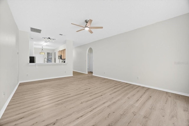 1760 Mountclair Ct, Mount Dora, FL 32757 - unfurnished living room featuring a ceiling fan, arched walkways, and light wood-style flooring