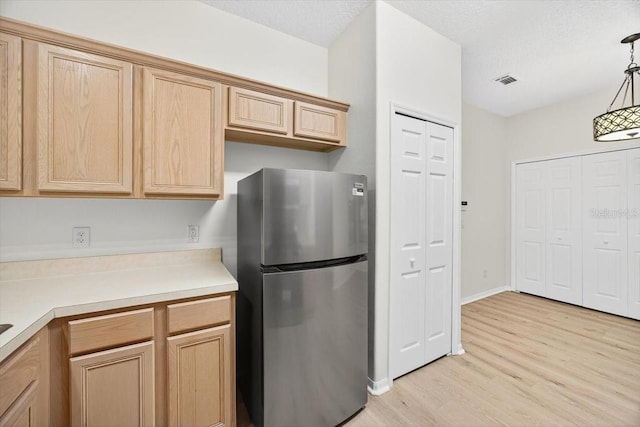 1760 Mountclair Ct, Mount Dora, FL 32757 - kitchen with freestanding refrigerator, light wood-type flooring, light countertops, light brown cabinetry, and hanging light fixtures