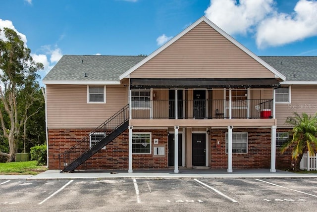 200 Country Club Dr Unit 1402, Largo, FL 33771 - rear view of house with brick siding, uncovered parking, stairs, and a shingled roof