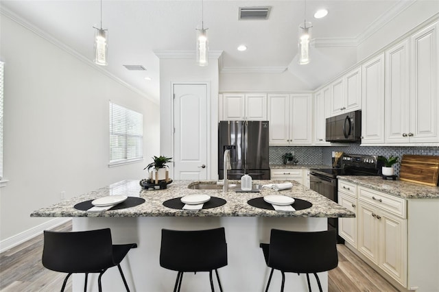 2405 W N B St Unit 1, Tampa, FL 33609 - kitchen featuring black appliances, crown molding, decorative backsplash, a breakfast bar area, and light wood-style flooring