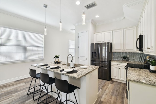 2405 W N B St Unit 1, Tampa, FL 33609 - kitchen with stainless steel refrigerator with ice dispenser, black microwave, decorative backsplash, light wood finished floors, and crown molding