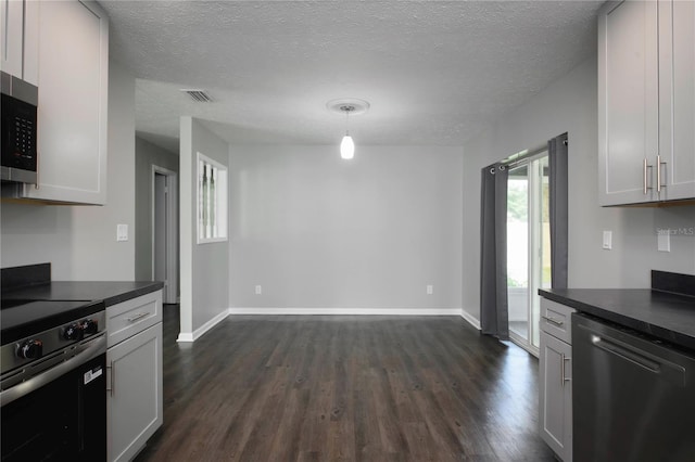 5018 Pine St, Seffner, FL 33584 - kitchen featuring stainless steel appliances, dark wood finished floors, dark countertops, a textured ceiling, and decorative light fixtures