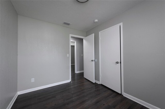 5018 Pine St, Seffner, FL 33584 - unfurnished bedroom featuring dark wood-style floors and a textured ceiling