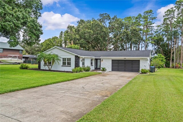 210 Lake Hobbs Rd, Lutz, FL 33548 - view of front facade featuring a garage, driveway, a front lawn, and stone siding