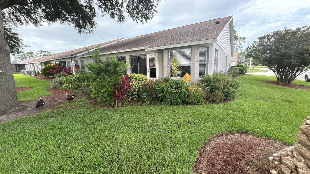 view of side of home featuring a yard and roof with shingles