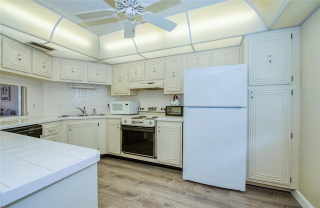 2206 Cordova Grn Unit 2206, Seminole, FL 33777 - kitchen with white appliances, under cabinet range hood, tile counters, and light wood-style flooring