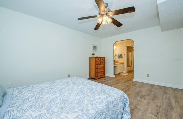 2206 Cordova Grn Unit 2206, Seminole, FL 33777 - bedroom with wood finished floors, arched walkways, a ceiling fan, and ensuite bathroom