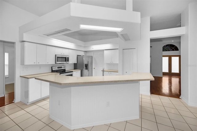 3612 Covington Dr, Holiday, FL 34691 - kitchen with appliances with stainless steel finishes, light tile patterned floors, light countertops, white cabinetry, and french doors