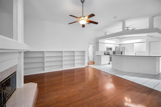 3612 Covington Dr, Holiday, FL 34691 - unfurnished living room with a ceiling fan, light wood-style floors, a fireplace, and built in shelves
