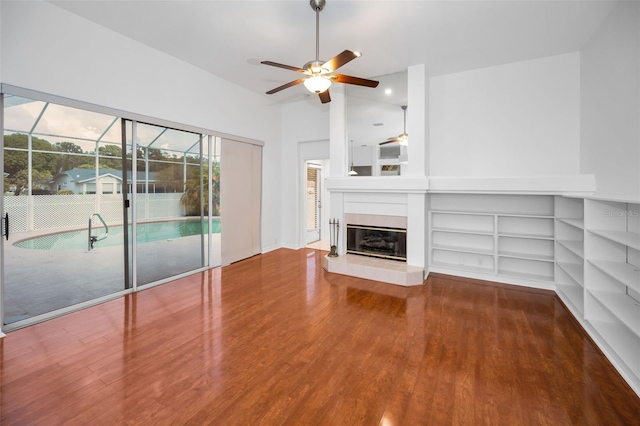 3612 Covington Dr, Holiday, FL 34691 - unfurnished living room featuring ceiling fan, wood finished floors, healthy amount of natural light, and a glass covered fireplace