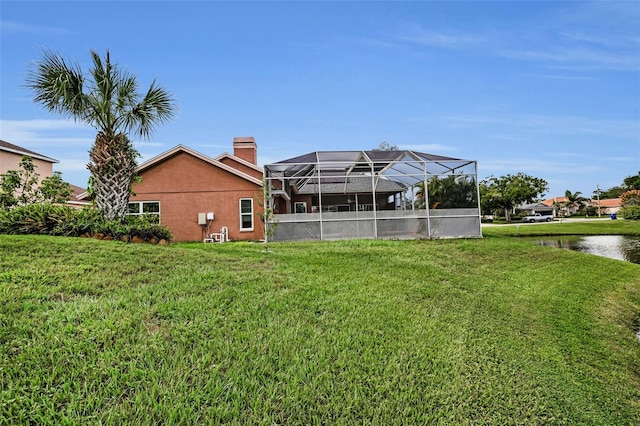 3612 Covington Dr, Holiday, FL 34691 - rear view of house featuring a water view, a lawn, a chimney, and glass enclosure