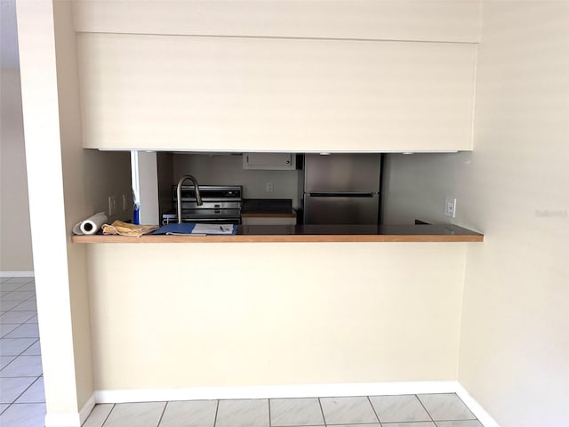 2525 W Bay Dr Unit A33, Largo, FL 33770 - kitchen with freestanding refrigerator, range, tile patterned flooring, and a peninsula