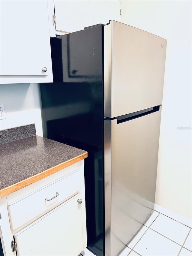 2525 W Bay Dr Unit A33, Largo, FL 33770 - kitchen with freestanding refrigerator, light tile patterned floors, white cabinetry, and dark countertops